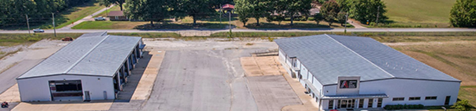 A building on left that is a 9,879 square foot shop and another building on the right that is a former dealership with offices and showroom that is 15,000 square feet located on 21.79 acres of land in Jonesboro, Arkansas at 5511 South Stadium Boulevard