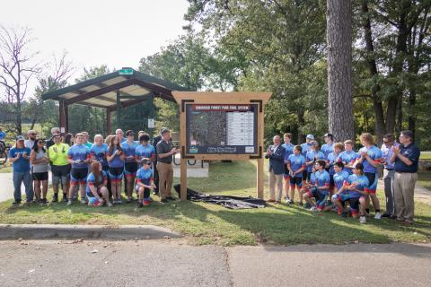 Jonesboro Unlimited, City Government, Chamber members, and Ridge Riders standing around new sign with trail system map on it