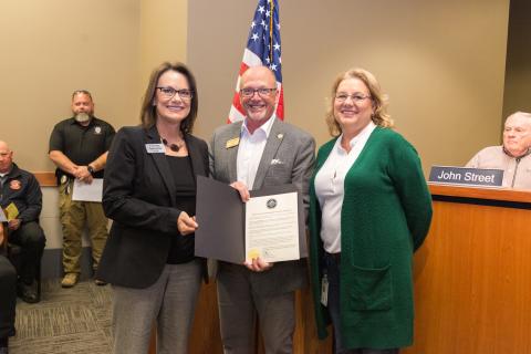 Christy Valentine of Hytrol and Tracey Crafton of TrinityRail stand beside Mayor Copenhaver who is holding the proclamation