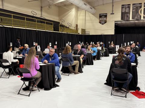 Employers conducting interviews one-on-one with students all throughout a section of a gym