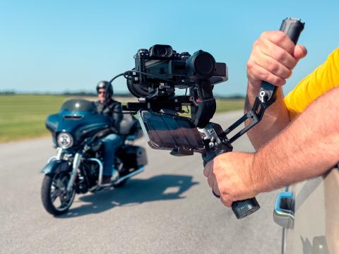 Camera held outside truck window recording video of motorcycle rider 