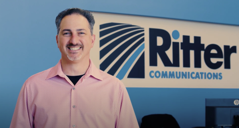 Victor Esposito standing in front of a Ritter Communications sign on the wall