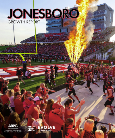 Cover of Jonesboro Growth Report shows A-State Football Players running out onto field while large pyrotechnic flame shoots upward at side of field