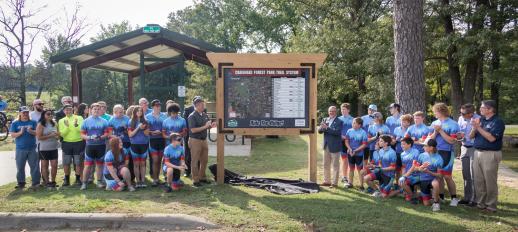 Jonesboro Unlimited, City Government, Chamber members, and Ridge Riders standing around new sign with trail system map on it