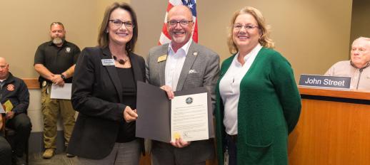 Christy Valentine of Hytrol and Tracey Crafton of TrinityRail stand beside Mayor Copenhaver who is holding the proclamation