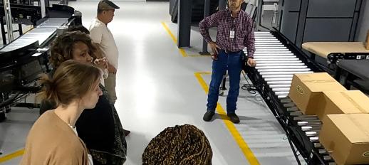 An employee of Hytrol shows teachers a simple conveyor and how it carries boxes