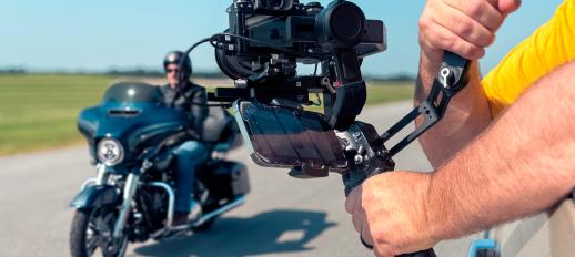 Camera held outside truck window recording video of motorcycle rider 