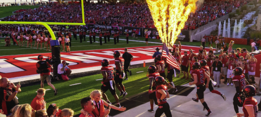 Cover of Jonesboro Growth Report shows A-State Football Players running out onto field while large pyrotechnic flame shoots upward at side of field