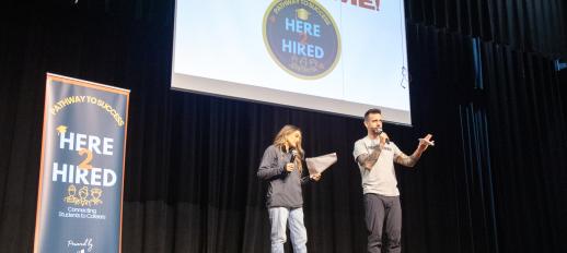 Chris Hughes and Bethania-Baray Harrison on stage at the kick off event with Here2Hired banner to left and above them